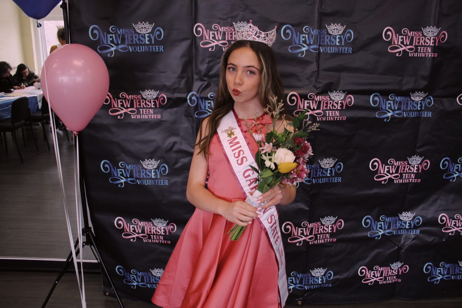 Kayla in her Miss Garden State Teen Volunteer sash holding flowers