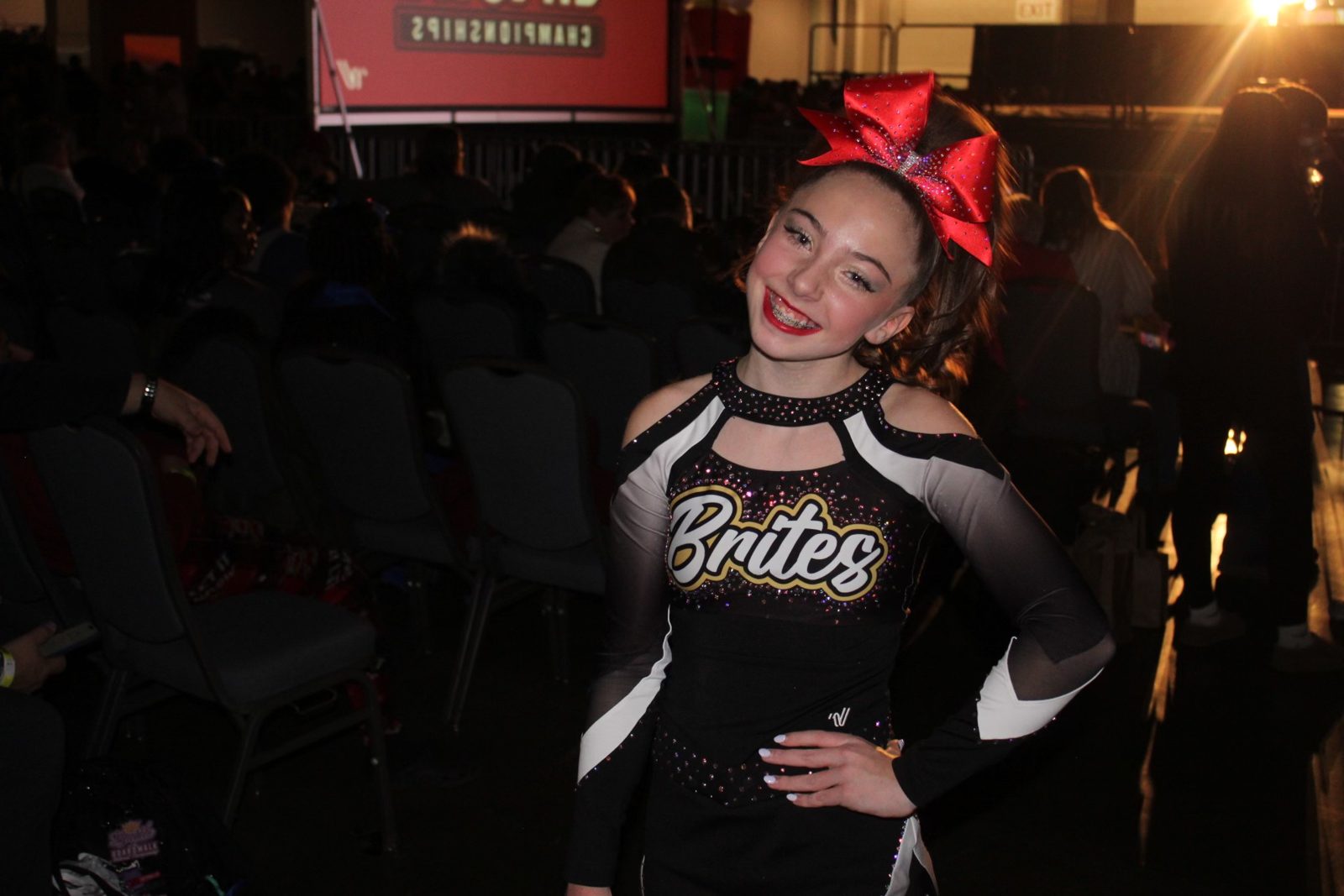 Kayla smiling in her Brites cheer uniform and red bow