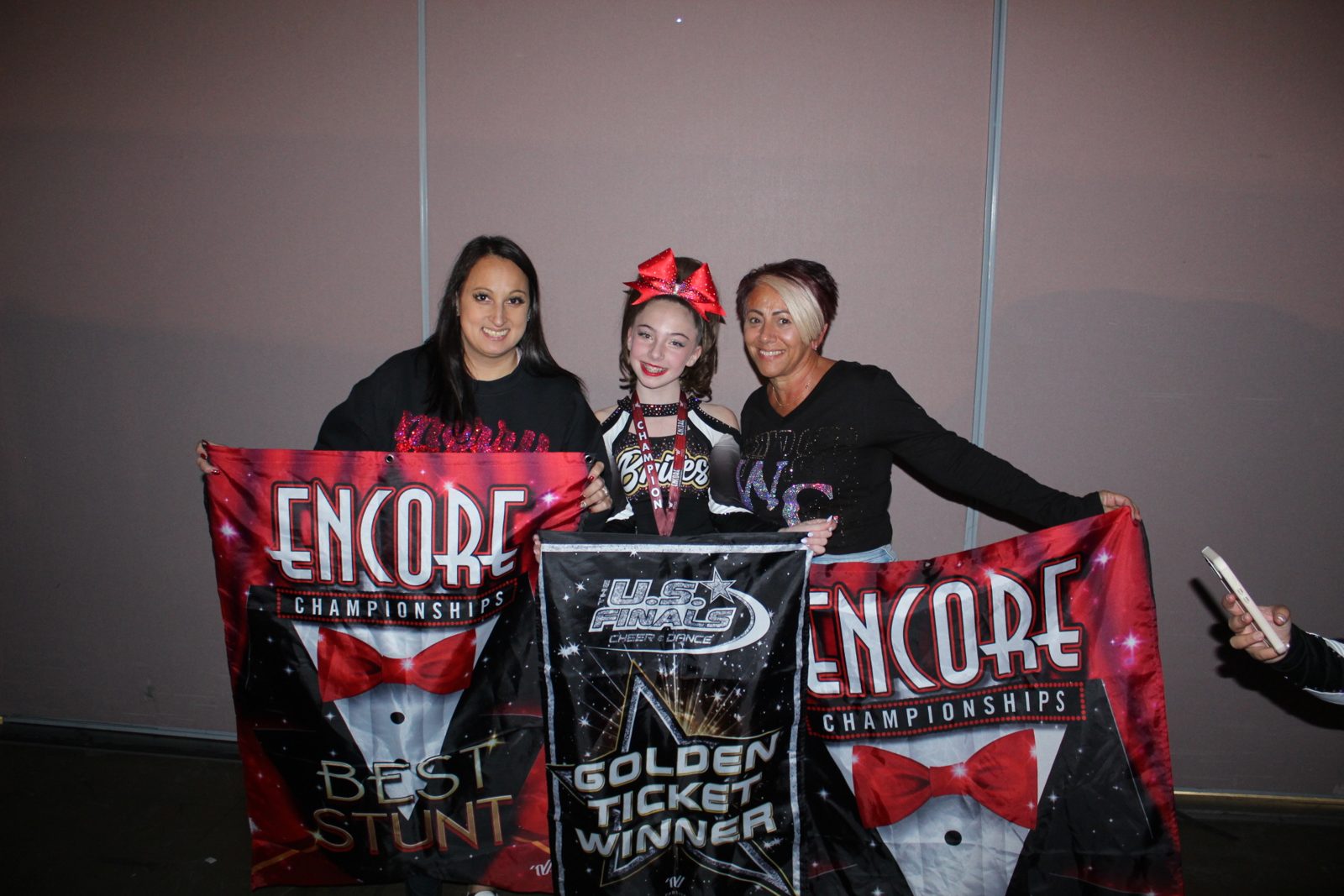 Kayla with coaches holding Encore Championships banners